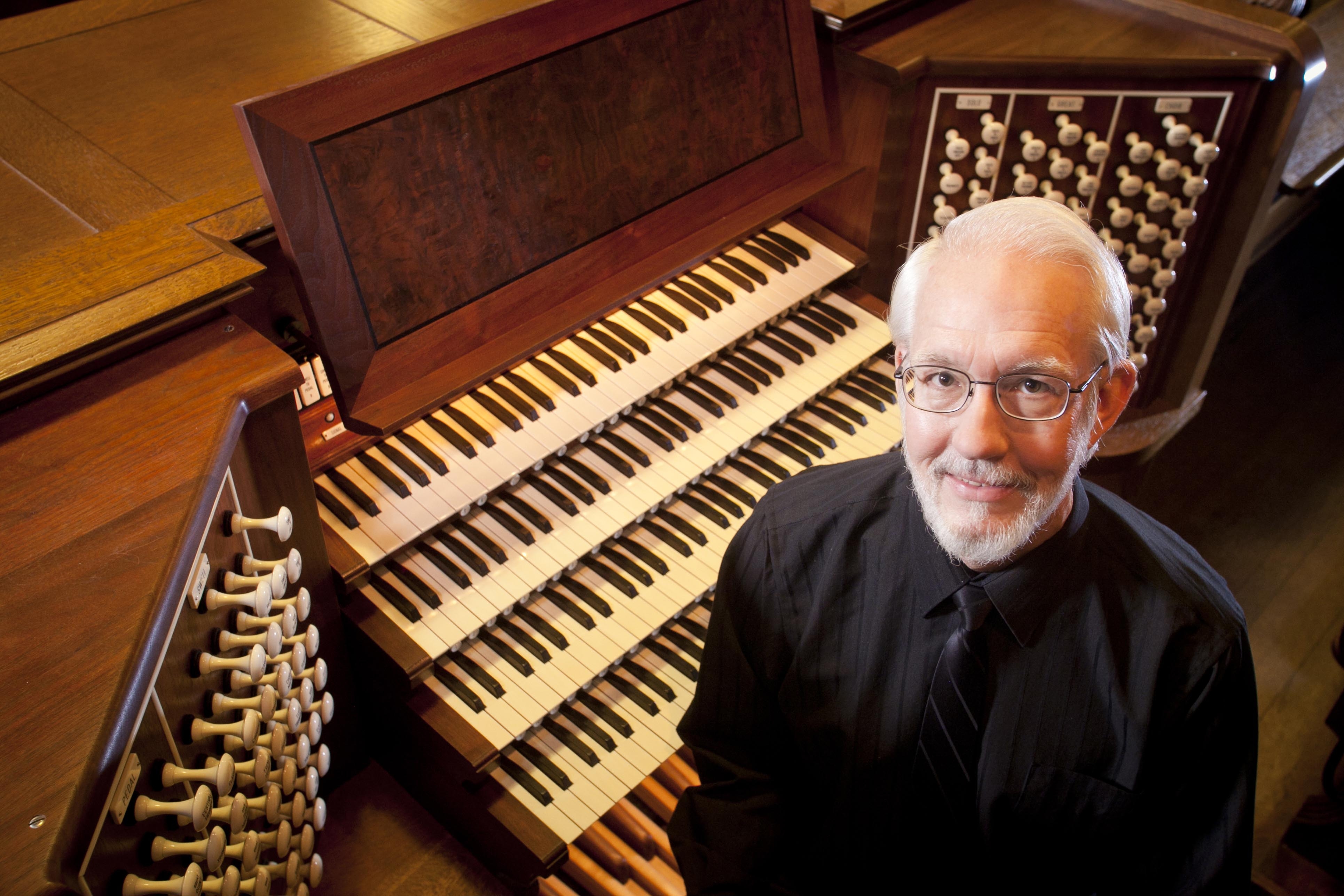 A man stands in front of an organ keyboard.