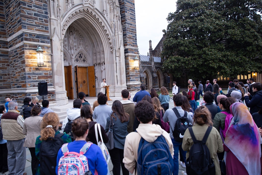 People listen to a speaker at a vigil on the steps of Duke Chapel
