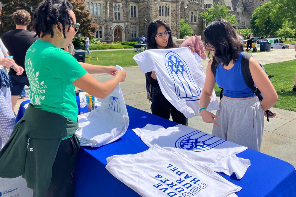 People hold t-shirts at a table in front of Duke Chapel