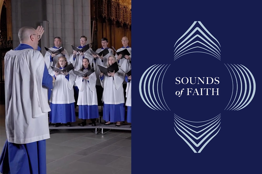 A man in a white and blue robe raises his hand front of a group of singers wearing the same robes.