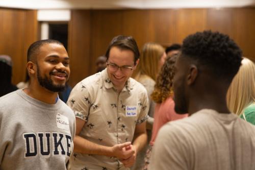 Two students look at each other with more students in the background.