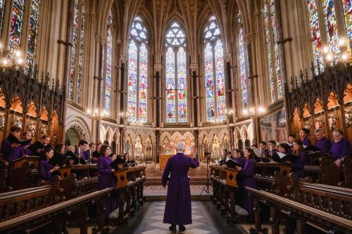A wide shot of a choir performing in a grand, ornate church. The choir, consisting of about 20 people in purple robes, is divided into two sections, one on the left and one on the right, facing a conductor who stands in the center with his back to the viewer.